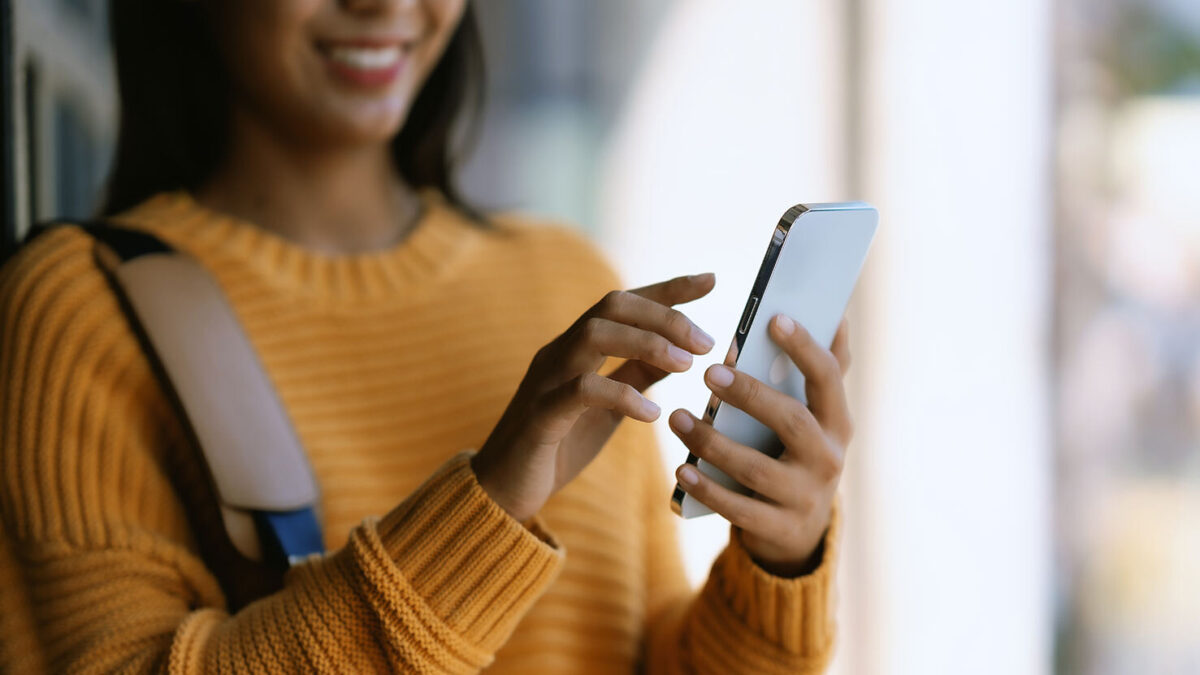 Eine Frau hält ein Smartphone in der Hand und tippt auf den Bildschirm.