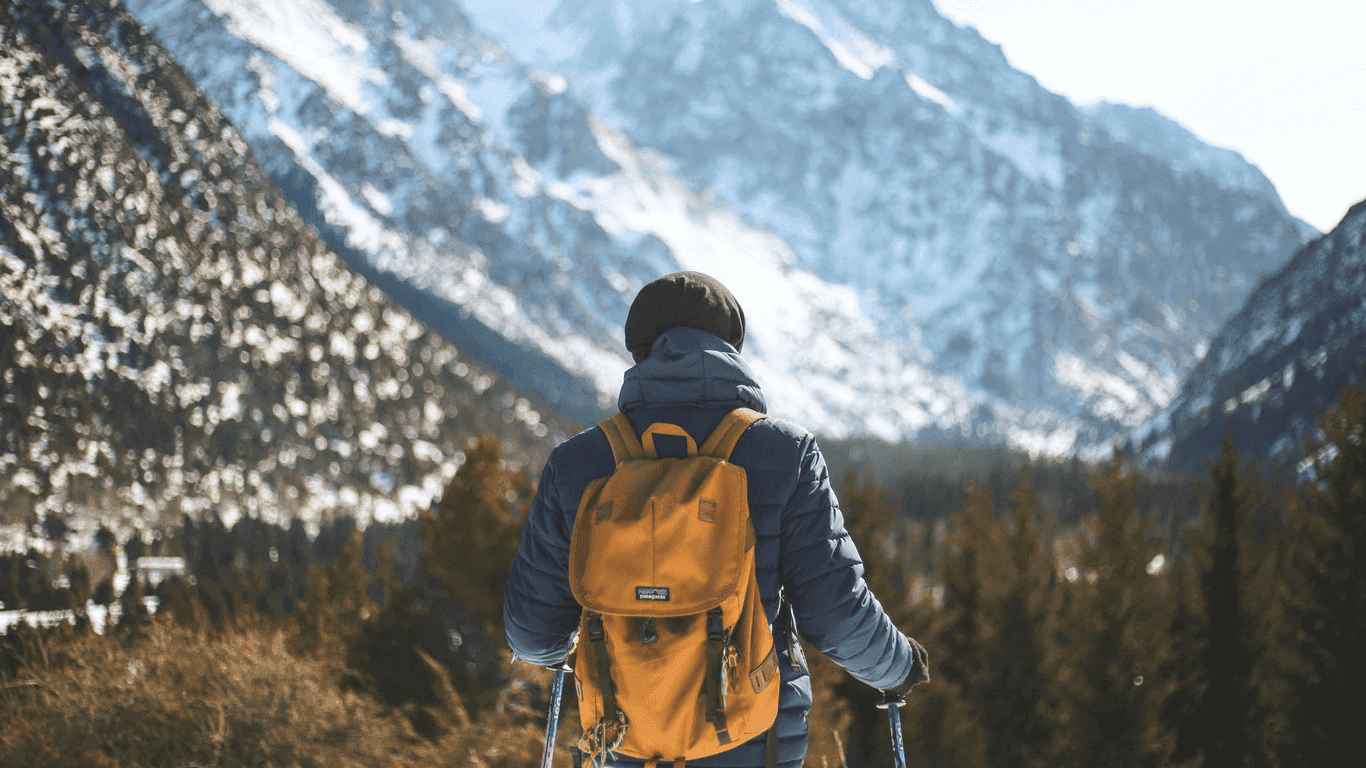 Das Bild zeigt einen Wanderer von hinten, mit Blick auf die Berg-Landschaft.