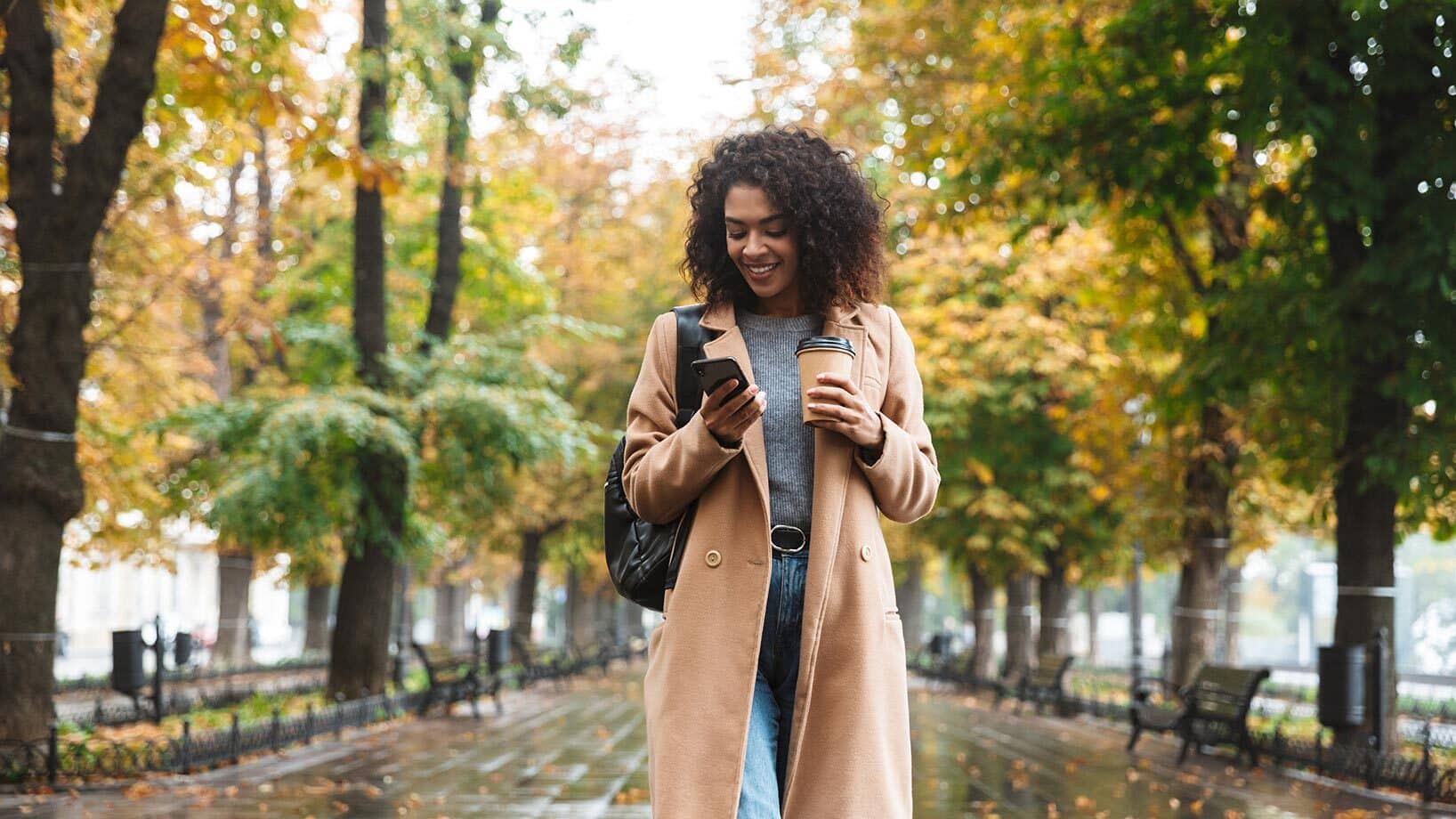 Das Bild stellt ein Beispiel für Mobile Commerce dar: Eine Frau shoppt unterwegs auf ihrem Smartphone.