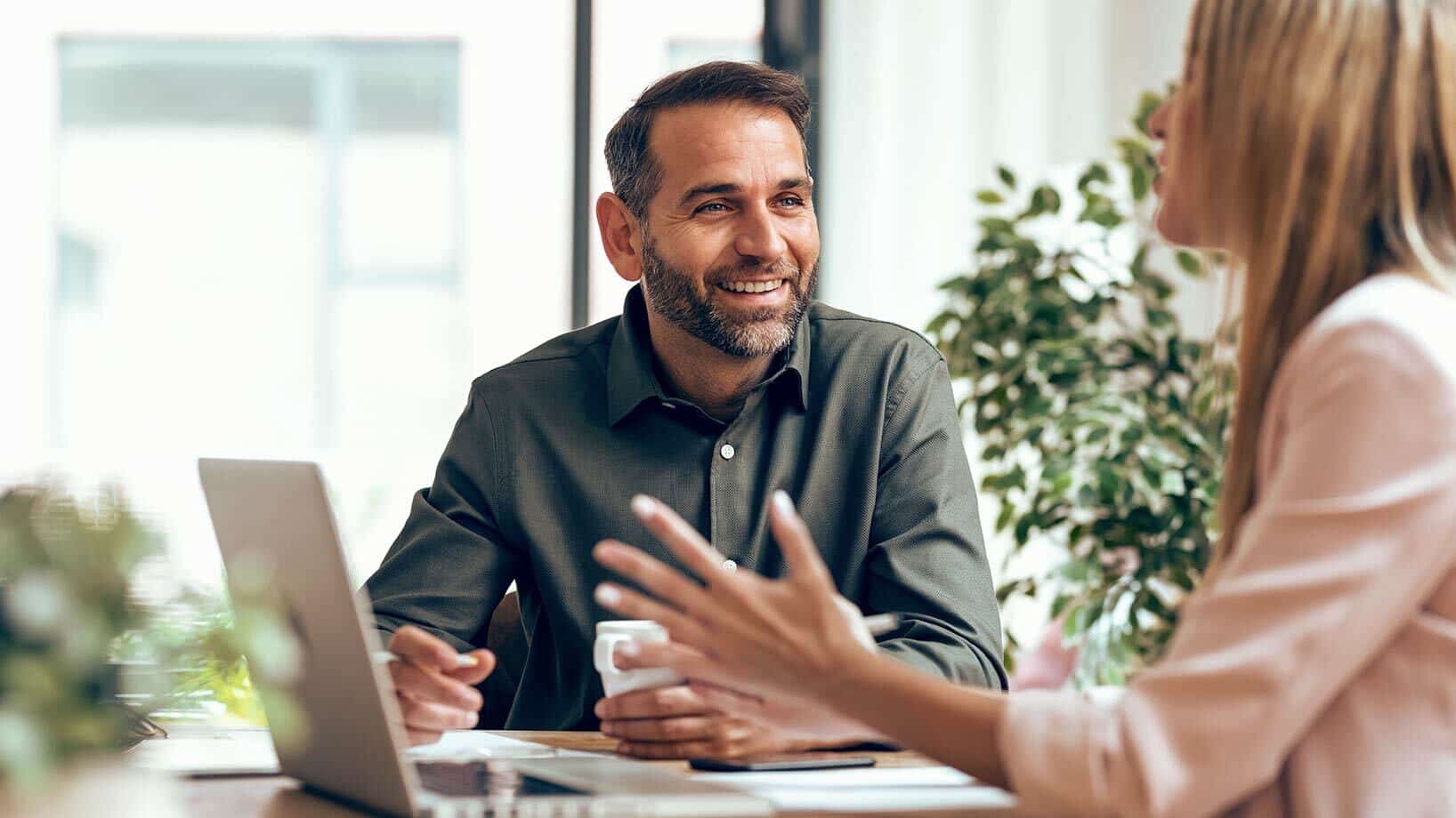 Ein Mann und eine Frau sitzen vor einem Laptop und sprechen über eine Onsite-Marketing-Kampagne.